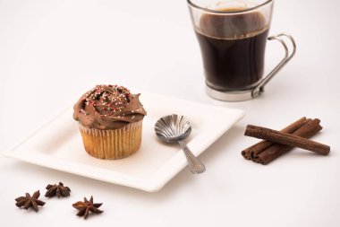 Sıcak kahveli çikolatalı kek, tarçın çubukları ve beyaz arka planda Anise yıldızları.