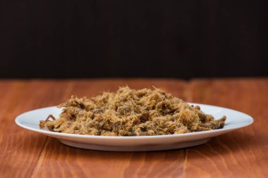 Ev yapımı tuzlu domuz eti, duvan cvarci, ahşap bir masada beyaz bir tabakta.