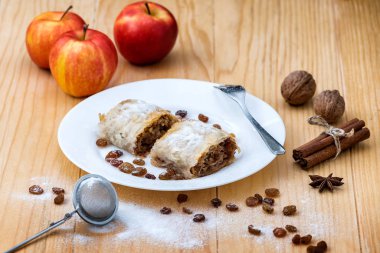 Elmalı turta, Apple Strudel. Elmalı, tarçınlı, cevizli ve kuru üzümlü turta, ahşap bir masada bir tabağa toz şeker serpiştirilmiş. 