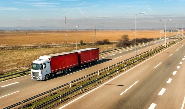 Kırsal kesimde güzel mavi gökyüzünün altında beyaz ve kırmızı bir kamyonet.