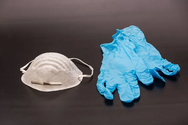Medical mask and rubber gloves on a black sterile surface. Corona virus protection. Healthcare and medical concept. Close up view of medical protection of face and hands - mask textile filter
