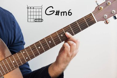 Gitar çalmayı öğren - Koyu mavi gömlekli bir adam beyaz tahtada gitar akorları çalıyor, Chord G diyez minor6 (G # m6)