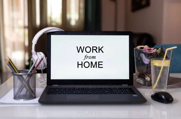 Work from home during Coronavirus pandemic quarantine isolation. Working remotely home concept. Comfortable working place in home office with laptop on the table with Headphones, lemonade