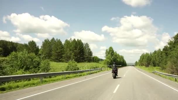 Een jonge fietser in een leren jas en een helm rijden op de motorfiets langs de snelweg rond de stad. Close-up Slowmotion — Stockvideo