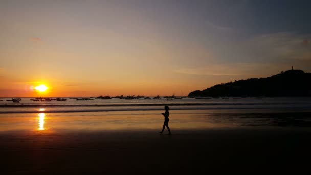 Personnes marchant au coucher du soleil sur la plage — Video