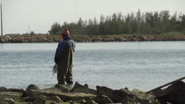 Laguna, pescador de pie en el agua — Vídeo de stock