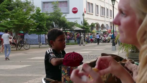 Маленький мальчик пытается продать конфеты — стоковое видео