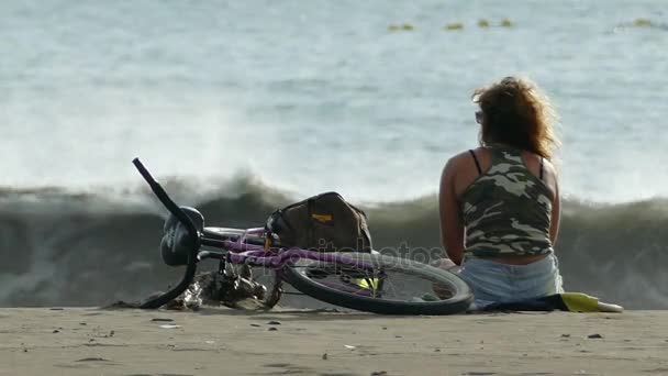 Femeie cu bicicleta întinsă pe plajă — Videoclip de stoc