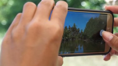 Asyalı kadın, San Vincente 'deki teknede cep telefonuyla video çekiyor.