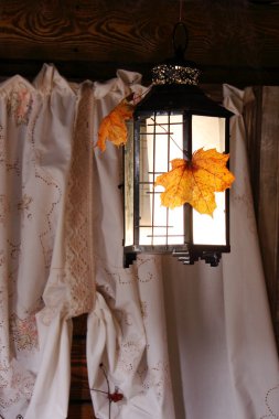 Penceredeki fener. Pencere perdelerinin arkasında parlayan bir fener. Sonbahar.