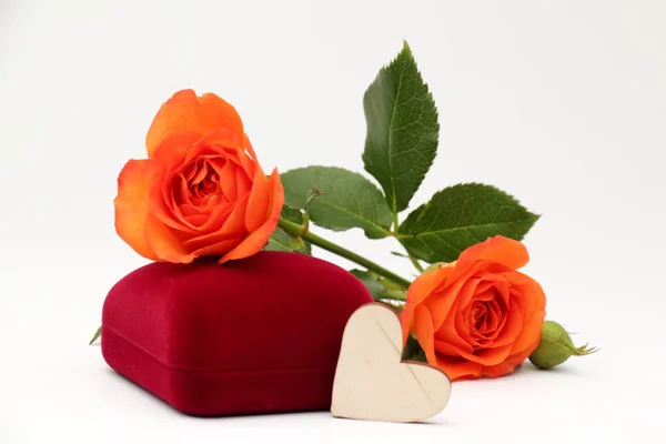 Box with jewelry gift and orange roses on a white background.