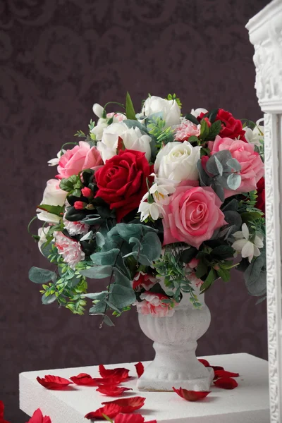 Vase of flowers and rose petals. Rose petals scattered on the table.