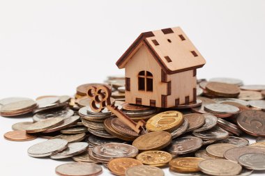 Ahşap ev ve sikkeler üzerinde anahtar.