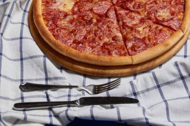 Bütün salamlı pizza ahşap bir masa dilimlenmiş.