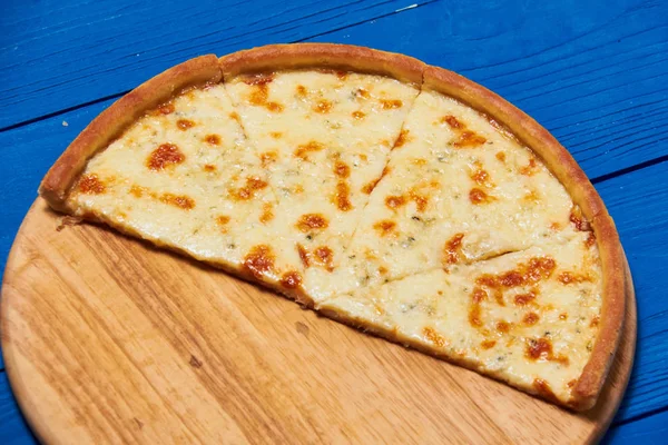 Pizza quattro fromaggi em uma placa de madeira . — Fotografia de Stock