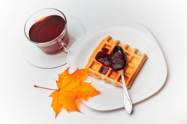 Bir fincan çay ve ahududu reçelli çıtır gofret. Beyaz tabaklar. Beyaz arkaplan.