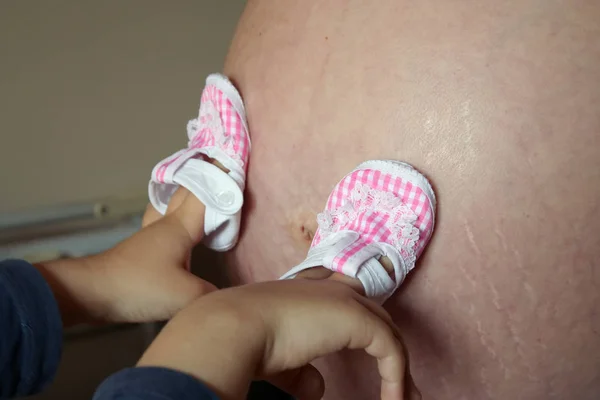 Moms belly and baby shoes.