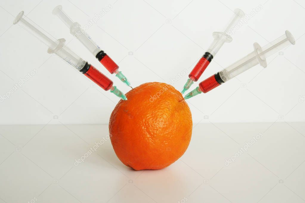 Orange and medical syringes. GMO fruit. GMO food ingredient.
