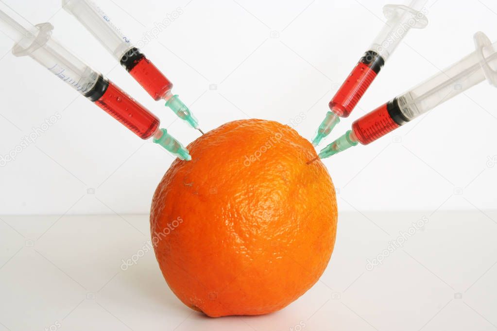 Orange and medical syringes. GMO fruit. GMO food ingredient.