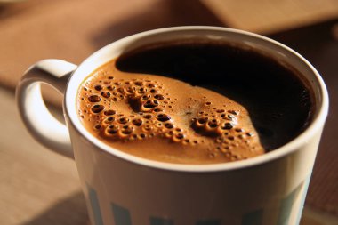 Bir fincan sıcak kahve. Bir fincan kahvenin üzerine güneş gölgesi..