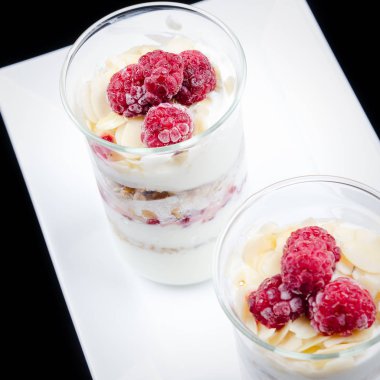 Granola çilek ve beyaz bir tabak ve siyah bir arka plan üzerinde bir bardak yoğurt ile