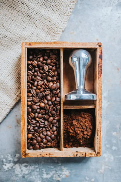 Freshly ground coffee, coffee beans and tamper — Stock Photo, Image