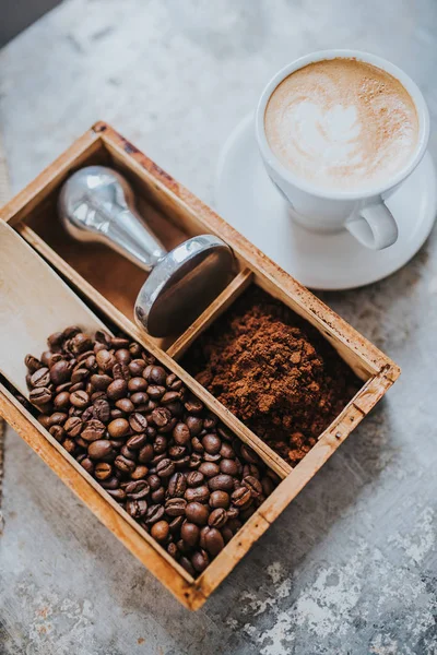 Kávová zrna, tamper a šálek lahodné kávy — Stock fotografie