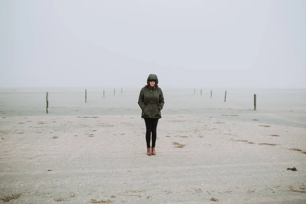 Mulher de pé na praia no tempo de inverno — Fotografia de Stock