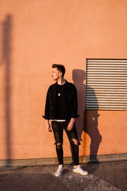 Turuncu duvarın önündeki genç adam.