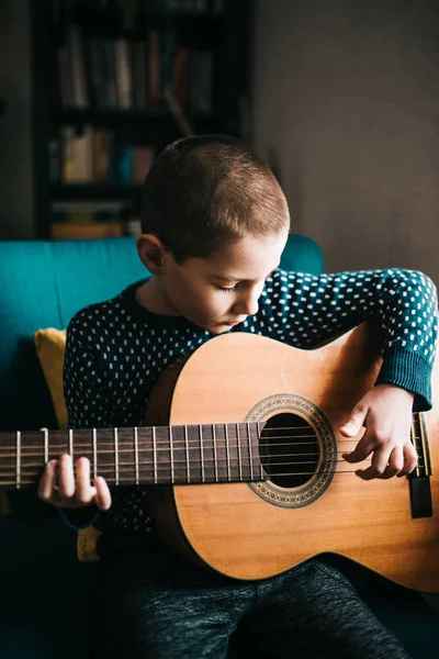 Portrait of little boy playing acoustic guitar at home — 图库照片