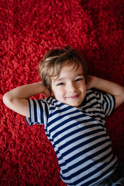 Kleine Jongen Liggend Een Rode Loper — Stockfoto