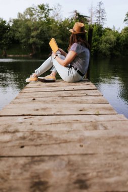 Nehir rıhtımında kitap okuyan genç bir kadın