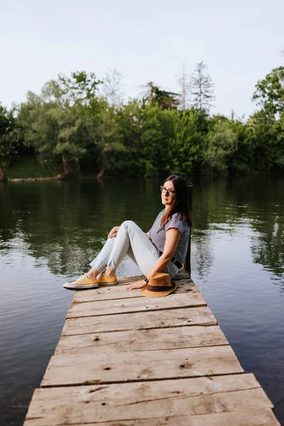 Young woman sitting on the river pier — Stock Image Young Woman Sitting River Pier Stock Photo
