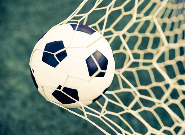 soccer ball in goal net with green grass - retro vintage filter 