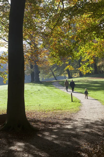 Paar en kleine jongen lopen in herfst park van manor darthuizen in — Stockfoto