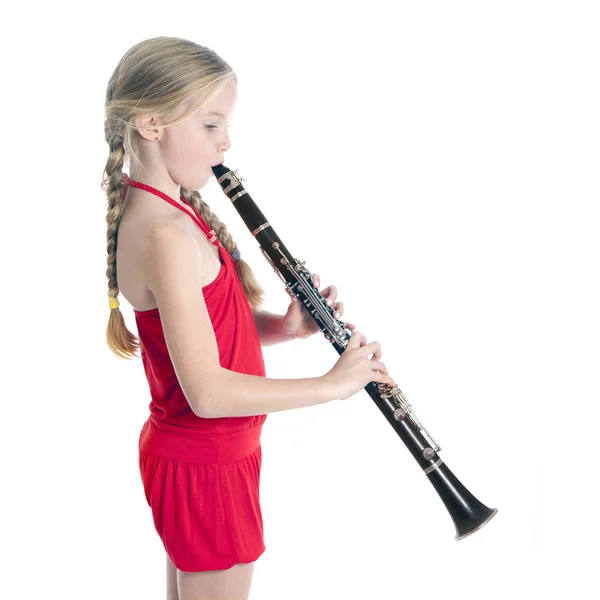 Giovane ragazza bionda in rosso suonare clarinetto — Foto Stock