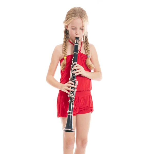 Giovane ragazza bionda in rosso suonare clarinetto — Foto Stock