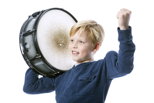 Young blond boy with drum against white background shows muscle — Stock Photo, Image