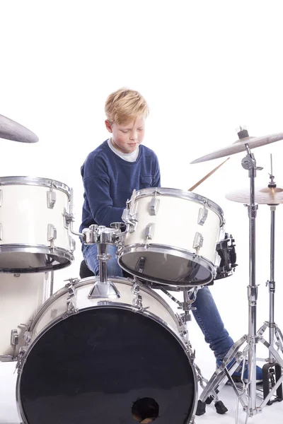 Young caucasian boy at drum kit in studio plays music — Stock Photo, Image