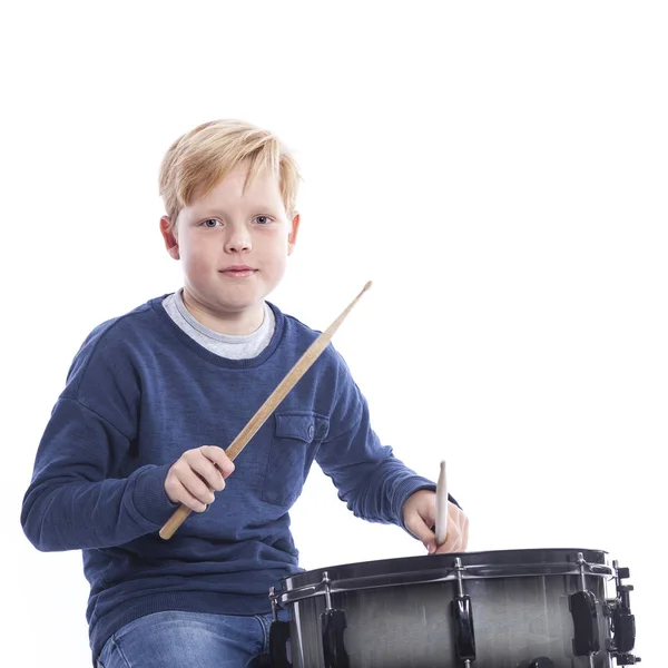 Jonge blonde jongen speelt drum tegen witte achtergrond — Stockfoto