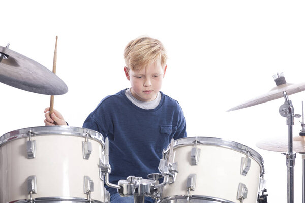 young caucasian boy at drum kit in studio plays music