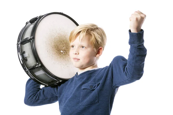 Young blond boy with drum against white background shows muscle — Stock Photo, Image