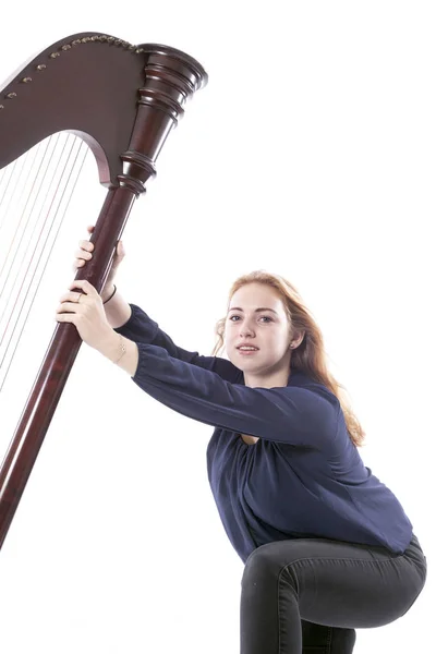 Vermelho loiro adolescente menina empurra harpa contra branco estúdio backgrou — Fotografia de Stock