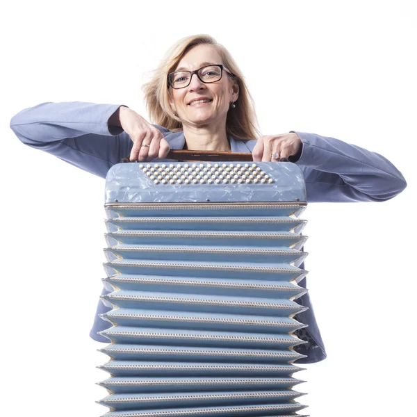 Woman in blue with glasses holds accordeon and smiles — Stock Photo, Image