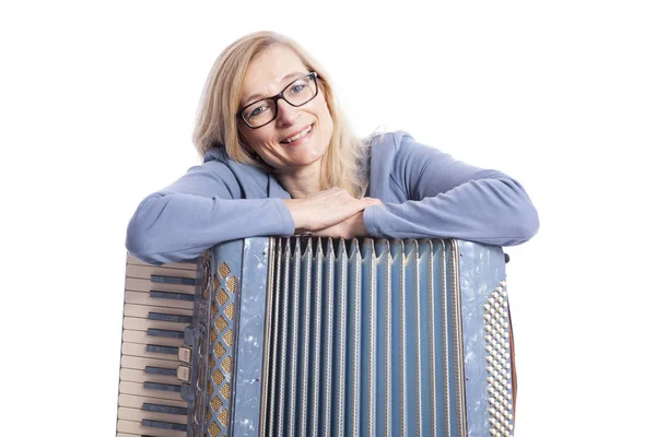 Woman in blue with glasses leans on accordeon and smiles — Stock Photo, Image