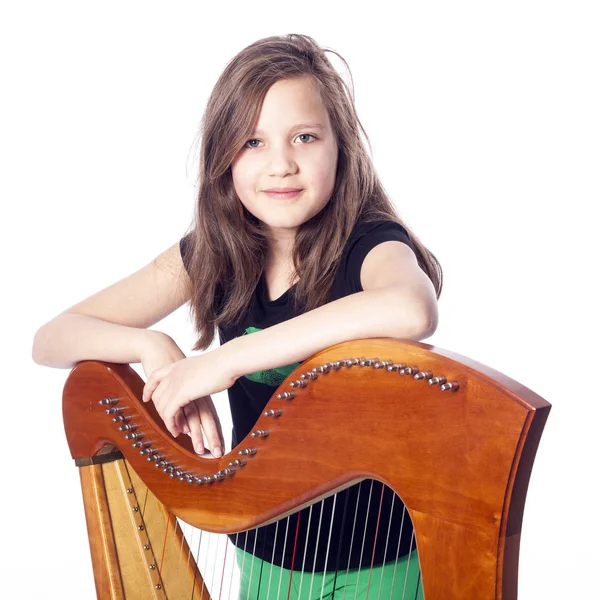 Mladá dívka v černé košili naklání na harfu ve studiu — Stock fotografie