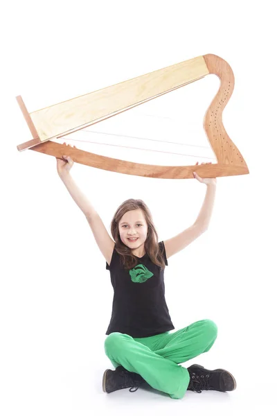 Jeune fille en pantalon vert soulève harpe en studio — Photo