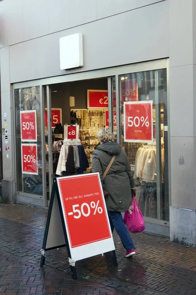 Utrecht, Nederländerna, 4 januari 2017: försäljning skyltar utanför klädaffär på regniga street och personer — Stockfoto