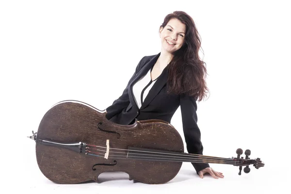 Bela mulher morena com violoncelo se senta no chão do estúdio agai — Fotografia de Stock