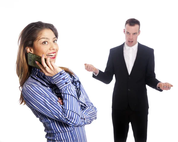 Young woman talks into mobile phone while boss looks from behind — Stock Photo, Image